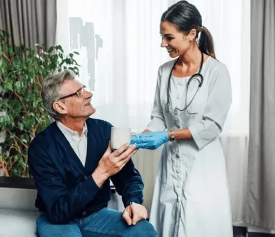 Nurse handing a cup to a seated patient during a Rhode Island consultation